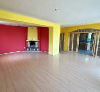 Na predaj 8 izbový rod. dom v lukratívnej časti - Rača - Obývačka v rodinnom dome s krbom, červenými stenami a drevenou podlahou na ulici.