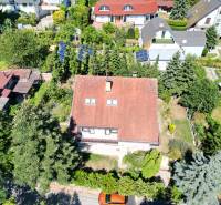 Na predaj 8 izbový rod. dom v lukratívnej časti - Rača - Popolná ulica, rodinný dom s červenou strechou, obklopený zeleňou a solárnymi panelmi.