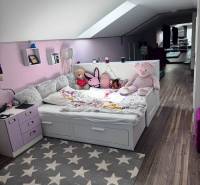 Priestranný 5-izbový rodinný dom s pohodlným dojazdom do Bratislavy  - Detská izba v rodinnom dome s posteľou, plyšovými hračkami a podlahou s dreveným dekorom.