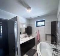 Priestranný 5-izbový rodinný dom s pohodlným dojazdom do Bratislavy  - Kúpeľňa v rodinnom dome s vaňou, umývadlom a skriňami na uskladnenie.