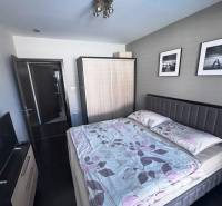 Priestranný 5-izbový rodinný dom s pohodlným dojazdom do Bratislavy  - Spálňa v rodinnom dome s tmavou podlahou, šedým čelom postele a dvomi obrazmi.