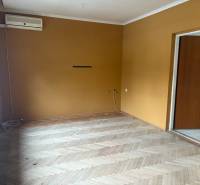 PREDAJ - Rodinný dom s investičným potenciálom - Nové Zámky - Izba s horčicovými stenami, podlaha s dreveným dekorom, klimatizácia v rodinnom dome.