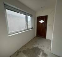 PREDAJ - 3-izbový rodinný dom po kompletnej interiérovej rekonštrukcii - Chodba v rodinnom dome s betónovou podlahou, drevenými dverami a plastovým oknom.