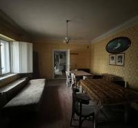 PREDAJ - Rodinný dom na rekonštrukciu s veľkým pozemkom – Kuraľany - Interiér rodinného domu s tapetami, jedálenským stolom a lavičkou pri okne.