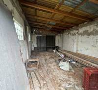 PREDAJ - Rodinný dom na rekonštrukciu s veľkým pozemkom – Kuraľany - Neudržiavaná miestnosť s drevenými trámami a zanedbaným vybavením v rodinnom dome.