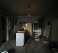 PREDAJ - Rodinný dom na rekonštrukciu s veľkým pozemkom – Kuraľany - Interiér rodinného domu s jednoduchou kuchyňou a podlahou s dreveným dekorom.