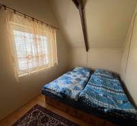 PREDAJ - Zrekonštruovaná rekreačná chata - Chľaba - Spálňa na chate s dvojlôžkom, bielymi stenami a podlahou s dreveným dekorom.