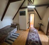 PREDAJ - Zrekonštruovaná rekreačná chata - Chľaba - Strešná izba Chaty s podlahou s dreveným dekorom, gaučom, kobercom a stolíkom.