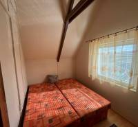 PREDAJ - Zrekonštruovaná rekreačná chata - Chľaba - Spálňa v chate s dvoma posteľami a veľkým oknom, závesy prepúšťajú svetlo.