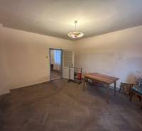 PREDAJ - Rodinný dom s veľkým pozemkom v obci Koplotovce  - Izba v rodinnom dome s podlahou s dreveným dekorom, stolom a stoličkami.