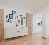 TOP - Rodinný dom s veľkým pozemkom - Dolný Hričov - Interiér rodinného domu s podlahou s dreveným dekorom, bielym nábytkom a dekoráciami.