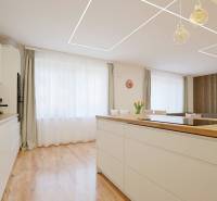 TOP - Rodinný dom s veľkým pozemkom - Dolný Hričov - Kuchyňa v Rodinnom dome s podlahou s dreveným dekorom, svetlým nábytkom a veľkým oknom.