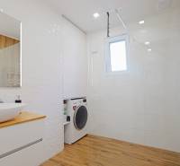 TOP - Rodinný dom s veľkým pozemkom - Dolný Hričov - Kúpeľňa s práčkou, sprchovým kútom, umývadlom a podlahou s dreveným dekorom v rodinnom dome.