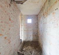 TOP - Rodinný dom s veľkým pozemkom - Dolný Hričov - Nedokončená miestnosť s holými tehlovými stenami v rodinnom dome.