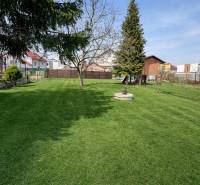 Rodinný dom s terasou, garáž, pozemok 902m2, Dojč, okr. Senica - Záhrada pri rodinnom dome v Dojči, trávnik s krbom a uskladneným drevom.