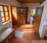 Zrekonštruovaný dom pri potoku v podhorí Veľkej Fatry - Chodba v rodinnom dome s dlažbou, drevenými dverami a lavicou.