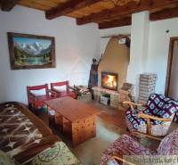 Zrekonštruovaný dom pri potoku v podhorí Veľkej Fatry - Obývačka s krbom v rodinnom dome, drevené trámy, kreslá, pohovka, obraz hôr.