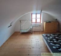 Zrekonštruovaný dom pri potoku v podhorí Veľkej Fatry - Podkrovná izba s oblúkovým stropom, podlaha s dreveným dekorom, posteľ, komoda.