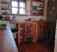 Zrekonštruovaný dom pri potoku v podhorí Veľkej Fatry - Rustikálna kuchyňa s keramickou dlažbou, drevenými policami a skrinkami.