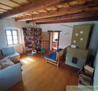 Zrekonštruovaný dom pri potoku v podhorí Veľkej Fatry - Drevený trámový strop, podlaha s dreveným dekorom, knižnica a kachle v rodinnom dome.