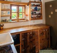 Zrekonštruovaný dom pri potoku v podhorí Veľkej Fatry - Kuchyňa v Rodinnom dome s drevenými policami a výhľadom na záhradu.