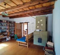 Zrekonštruovaný dom pri potoku v podhorí Veľkej Fatry - Drevené trámy na strope, podlaha s dreveným dekorom, kachle a knihovňa.