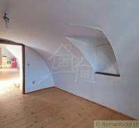 Zrekonštruovaný dom pri potoku v podhorí Veľkej Fatry - Podkrovie rodinného domu s podlahou s dreveným dekorom a šikmým stropom.