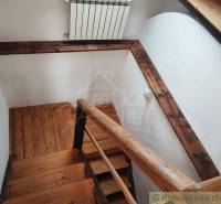 Zrekonštruovaný dom pri potoku v podhorí Veľkej Fatry - Drevené schodisko so zábradlím v Rodinnom dome s podlahou s dreveným dekorom.