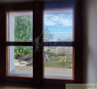 Zrekonštruovaný dom pri potoku v podhorí Veľkej Fatry - Výhľad z okna na záhradu rodinného domu v Blatnici so stromami a oblohou.