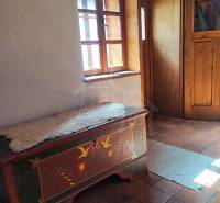 Zrekonštruovaný dom pri potoku v podhorí Veľkej Fatry - Tradičný interiér rodinného domu s maľovanou truhlou a hlinenou podlahou.