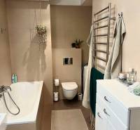 Prenájom 2,5 izbový byt, Trenčianska ulica, Bratislava II. Ružinov - Kúpeľňa v 2-izbovom byte s vaňou, zelenými rastlinami a úložnými skrinkami.