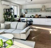 Prenájom 2,5 izbový byt, Trenčianska ulica, Bratislava II. Ružinov - Obývačka s kuchyňou v 2-izbovom byte, svetlý nábytok, podlaha s dreveným dekorom.