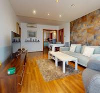 Predaj, 4izbový byt  Fončorda, Banská Bystrica - Obývacia izba v 4-izbovom byte s pohodlnou sedačkou a podlahou s dreveným dekorom.