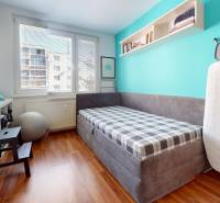 Predaj, 4izbový byt  Fončorda, Banská Bystrica - Malá izba so sivým gaučom, poličkami a podlahou s dreveným dekorom v 4-izbovom byte.