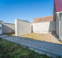 RD PO REKONŠTRUKCII spolu so STAVEBNÝM POZEMKOM na druhý dom - takmer  - Dvor rodinného domu na Kupeckého ulici v Pezinku s bránou a trávnatou plochou.