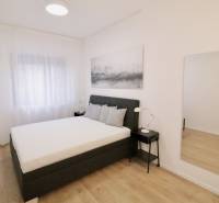 Komfortne vybavený 2-izbový byt v projekte 2 Sýpky - Svetlá spálňa s veľkým lôžkom a podlahou s dreveným dekorom v 2-izbovom byte.