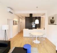 Komfortne vybavený 2-izbový byt v projekte 2 Sýpky - Obývacia izba s podlahou s dreveným dekorom, kuchynskou linkou a jedálenským stolom v 2-izbovom byte.