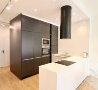 Komfortne vybavený 2-izbový byt v projekte 2 Sýpky - Kuchyňa v 2-izbovom byte s priestrannou kuchynskou linkou a podlahou s dreveným dekorom.