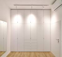 Komfortne vybavený 2-izbový byt v projekte 2 Sýpky - Spálňa s bielou vstavanou skriňou a podlahou s dreveným dekorom v 2-izbovom byte.