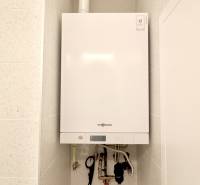 Komfortne vybavený 2-izbový byt v projekte 2 Sýpky - Biely kotol namontovaný na stene v 2-izbovom byte, s dlažbou okolo.