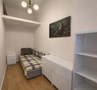 Predaj 4+1 izbový byt, 110 m2, 2 balkóny, Obchodná ul, centrum BA - Izba v 4-izbovom byte s kreslom, poličkami a podlahou s dreveným dekorom.