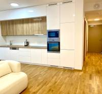 I 3 i byt s parkovaním v rezidenčnom komplexe METROPOLIS - Štýlová kuchyňa s bielymi skrinkami, spotrebičmi a podlahou s dreveným dekorom v 3-izbovom byte.