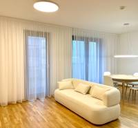 I 3 i byt s parkovaním v rezidenčnom komplexe METROPOLIS - Svetlá obývacia izba v 3-izbovom byte s bielou sedačkou a podlahou s dreveným dekorom.