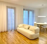 I 3 i byt s parkovaním v rezidenčnom komplexe METROPOLIS - Obývacia izba s béžovou pohovkou, okrúhlym stolom a podlahou s dreveným dekorom.