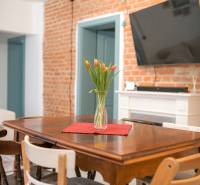 Na predaj zrekonštruovaný dom na Štefánikovej ulici, Trenčín - Jedálenský stôl s vázou tulipánov, tehla, TV na stene v rodinnom dome.