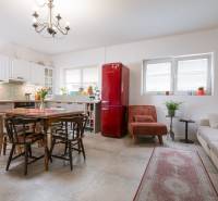 Na predaj zrekonštruovaný dom na Štefánikovej ulici, Trenčín - Kuchyňa v rodinnom dome s bielymi skrinkami, červenou chladničkou a dreveným stolom.