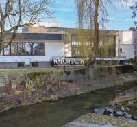 Predaj, polyfunkcia/obchodné priestory Považská Byst... - Obchodné priestory v Považskej Bystrici pri potoku obklopené stromami a zelenou vegetáciou.