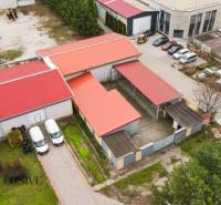 PRAKTICKÉ SKLADOVÉ PRIESTORY  | DOPRAVNÁ | TOPOĽČANY - Priemyselný areál na ulici s halami a skladmi, autá zaparkované v blízkosti budov.