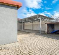 PRAKTICKÉ SKLADOVÉ PRIESTORY  | DOPRAVNÁ | TOPOĽČANY - Nádvorie na ulici Dopravná s prístreškom, sklady a haly, jasná obloha, stromy bez listov.