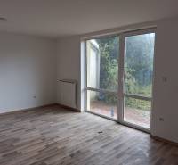 PREDAJ – 4-izbový rodinný dom v radovej zástavbe s garážou - Izba s podlahou s dreveným dekorom v rodinnom dome a výhľadom do záhrady.